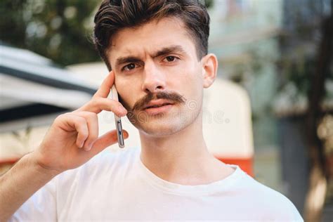 Portrait Of Young Amazed Mustache Man In Withe T Shirt Talking On