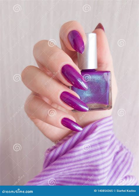 Female Hand With Purple Long Nails And Nail Polish Bottle Stock Image