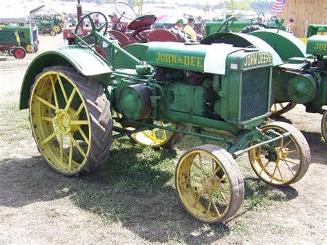 An Old Green And Yellow Tractor Parked On Top Of A Grass Covered Field