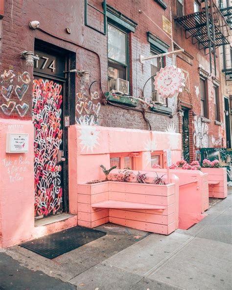 some pink benches on the side of a building with lots of graffitti written on it