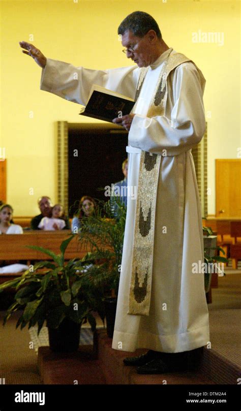 A Robed Catholic Priest Gestures While Reading A Sermon At A Church