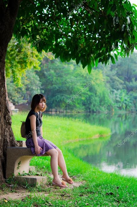 Cute Thai Girl Is Sitting Alone Under The Tree Near The River B Stock