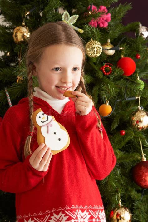 Girl Eating Cookie In Front Of Christmas Tree Stock Photo Image Of