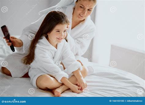 Happy Mother And Daughter Tidy Up After Shower Together On Bed Stock