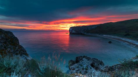 Landscape View Of Sea Coast Mountains In Yellow Red Clouds Sky