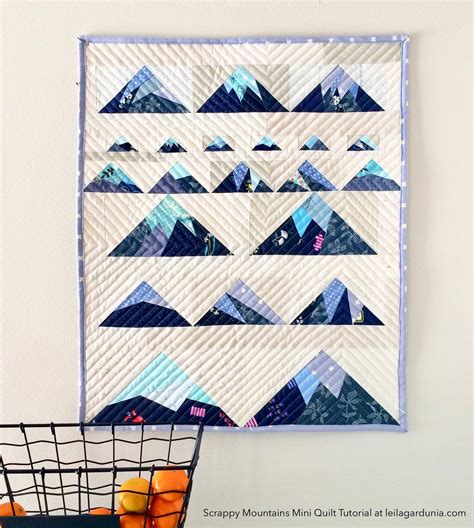 A Quilted Wall Hanging Next To A Basket With Oranges On It And The