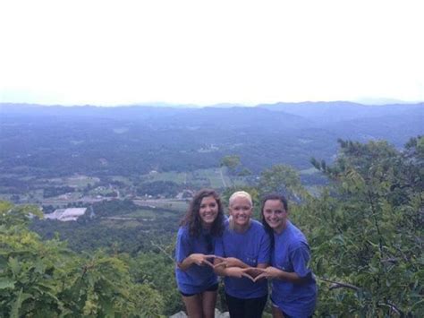 Three People Standing On Top Of A Mountain