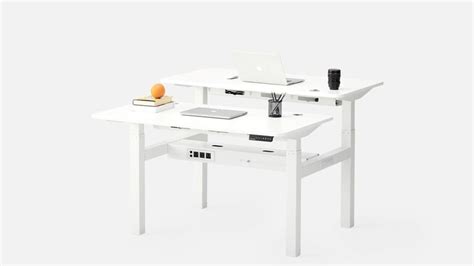 A White Desk With A Laptop On It And An Orange In Front Of The Desk