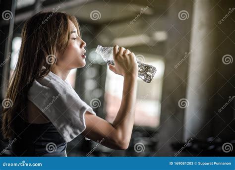 Young Athletic Fitness Woman Drinking Water From Bottle In Gym Stock