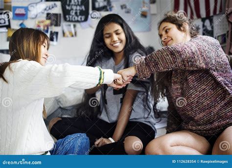 Teenage Girls In A Bedroom Fist Bumping Friendship Concept Stock Photo