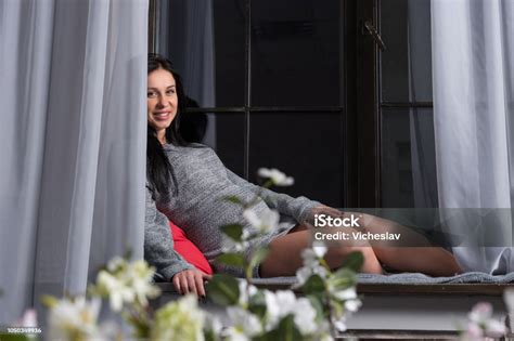 schönes lächeln schwangere brünette frau in ein strickkleid sitzt auf der fensterbank stockfoto