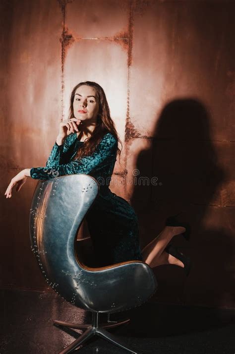 Attractive Young Woman In A Velvet Dress Sitting In A Leather B Stock