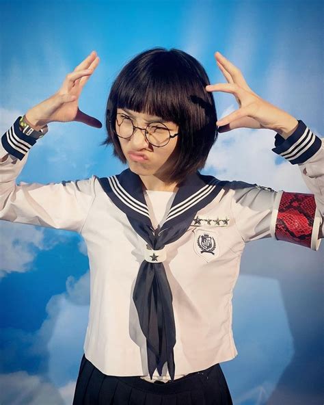 A Woman Wearing Glasses And A Sailor Uniform With Her Hands In The Air