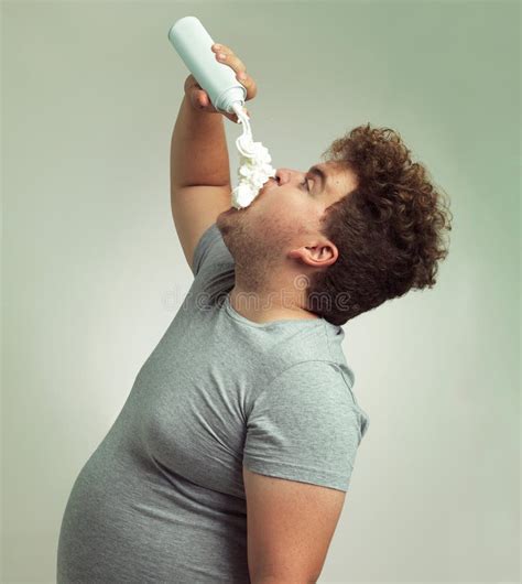 im on the whipped cream diet an overweight man filling his mouth with whipped cream stock