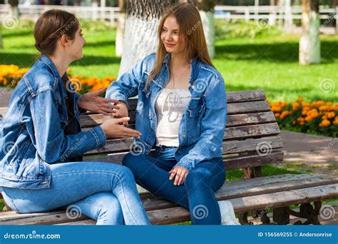 two beautiful girlfriends are talking in a park sitting on a bench stock image image of couple