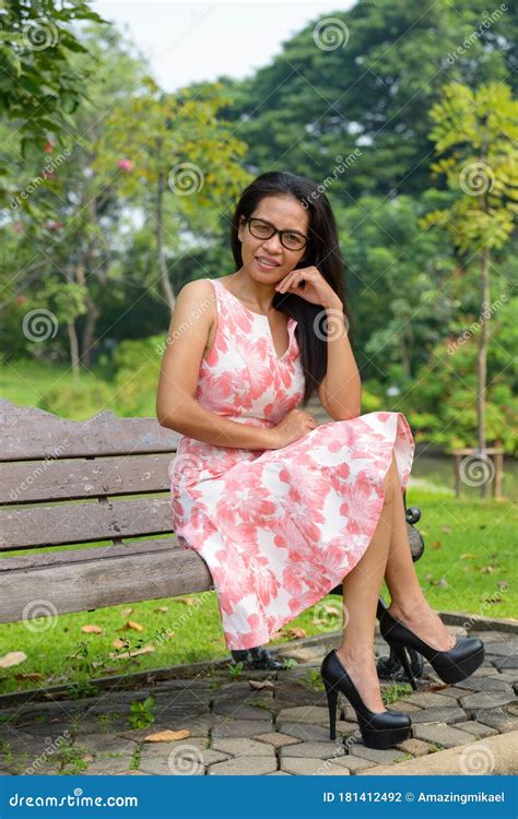 Happy Mature Asian Woman Relaxing At The Park Outdoors Stock Photo