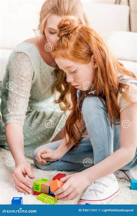 beautiful redhead mother and daughter playing with constructor on floor at home stock image