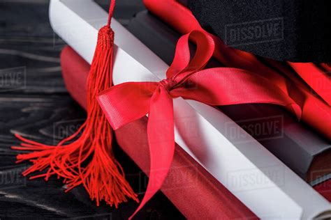 Graduation Hat And Diploma With Red Ribbon On Stack Of Books Stock