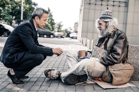 Pleasant Short Haired Rich Man In Costume Supporting Miserable Homeless Stock Image Image Of