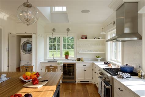 Stacked washer and dryer hidden behind a black barn door on rails in a cottage basement boasting green cabinets and light oak wood floors. 4 Ways to Hide the Laundry - On the Drawing Board