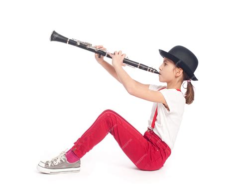 Маленькая девочка играет на кларнете на белом фоне Премиум Фото