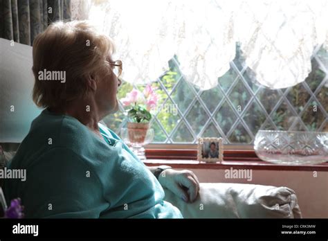 Mature Woman Sitting Alone Looking Out Of The Window Through Net