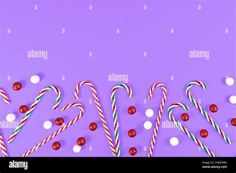 Christmas Candy Canes And Ornament Balls At Bottom Of Purple Background