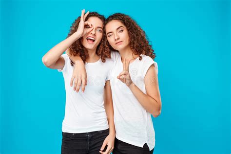 Two Surprised Girls Twins Pointing Finger Away Over Blue Background Stock Image Image Of