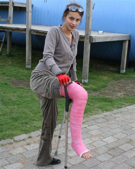 A Woman With Crutches And Pink Cast On Her Leg Is Holding An Object