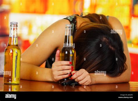 Portrait Of A Drunk Woman Sleeping Over A Wooden Table And Holding An Open Beer With Her Hand