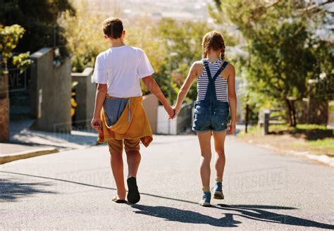 Boy And Girl Walking On An Empty Road Together Kids In