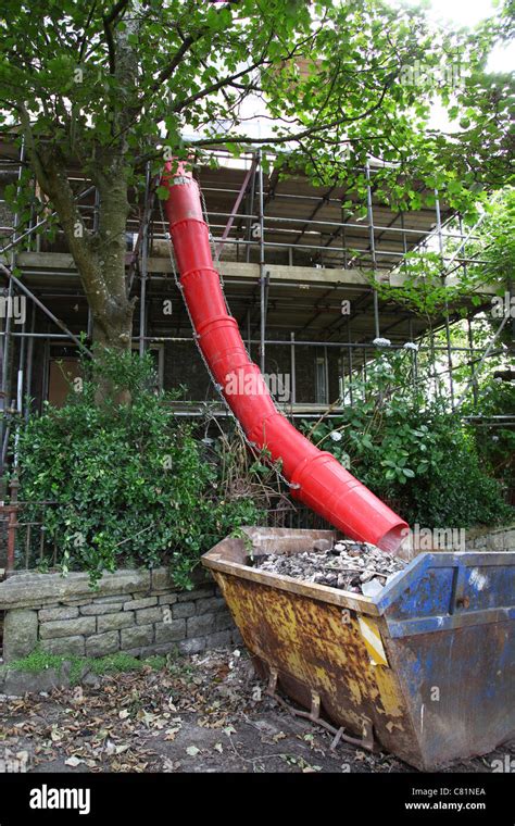 A Red Builders Chute Channeling Rubble Into A Skip St Just Cornwall