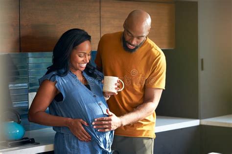 Loving African American Husband With Pregnant Wife At Home In Kitchen