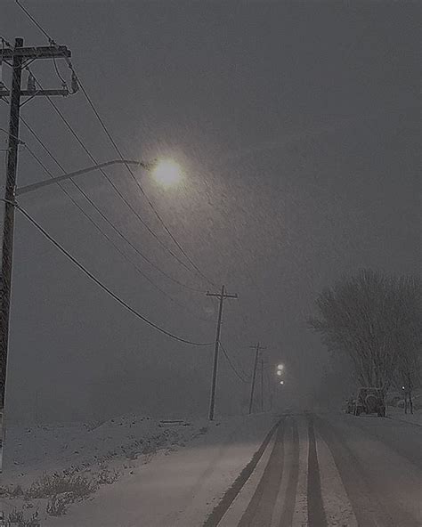 A Street Light On A Snowy Night With Power Lines And Telephone Poles In