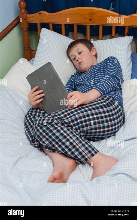 A Nine Year Old Boy Using His Ipad Tablet In His Bedroom Stock Photo