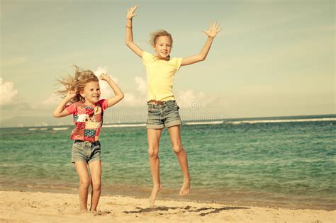 Petites Filles Heureuses Sautant Sur La Plage Photo Stock Image Du Espi Gle Bonheur