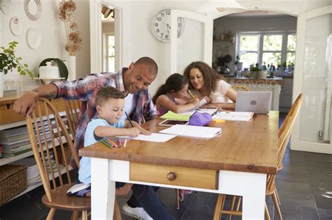 Parents Helping Children With Homework At Table Stock Photo By