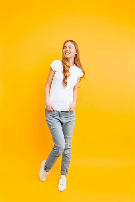Full Length Portrait Of A Cheerful Beautiful Girl Posing On A Yellow