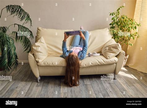 Little Girl Lying Upside Down On Sofa Stock Photo Alamy