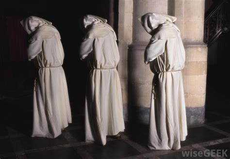 three monks walking with hoods up monk statue photo