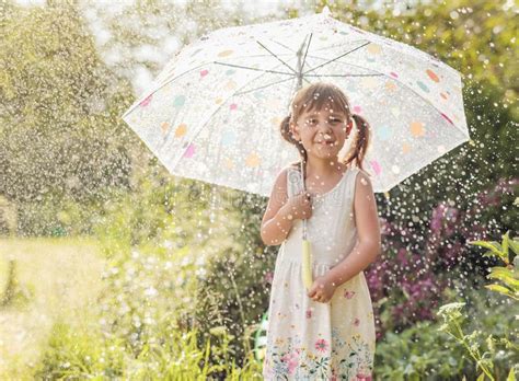 Happy Little Girl In Garden Under The Summer Rain With An Umbrella