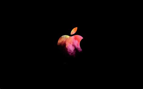 An Apple Logo Is Shown In The Dark With Red And Pink Paint On Its Side
