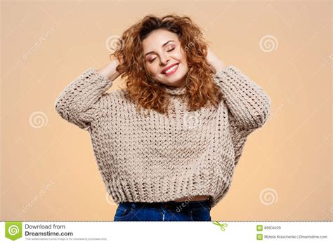 close up portrait of cheerful smiling beautiful brunette curly girl in knitted sweater over