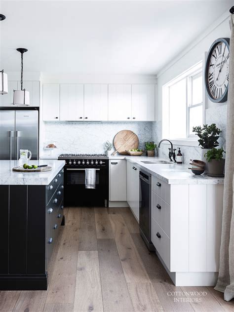A dark and rich floor with bright white furniture and cabinets lays down the foundation of this cozy and inviting kitchen. Modern Scandi-Inspired White Farmhouse Design - DigsDigs