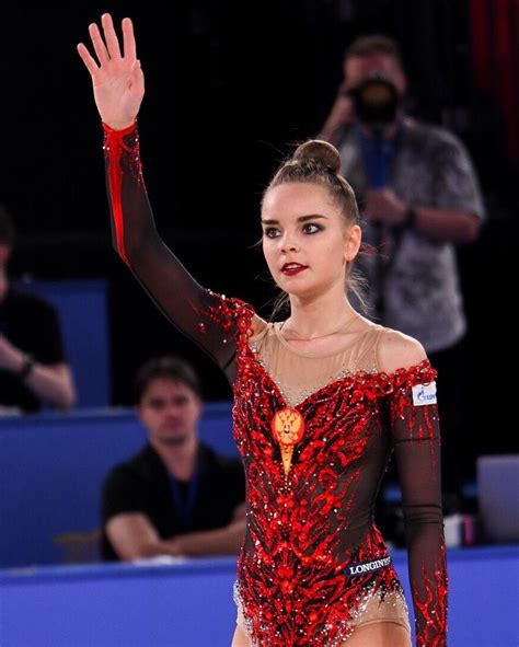 a woman in a red and black leotard is holding her hand up to the sky