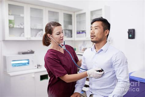 Female Nurse Using Stethoscope On Male Patient Photograph By Caia Image