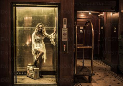 Woman Standing In Elevator In Hotel With Suitcase Stock Photo