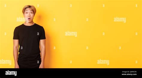 Portrait Of Startled Handsome Asian Blond Guy Drop Jaw And Gasping Impressed Yellow Background