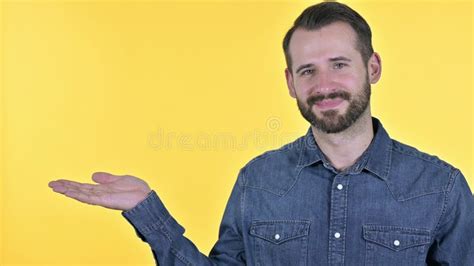 The Portrait Of Young Man Holding Product On Hand Yellow Background