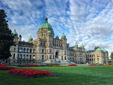 A Large Building With Green Roof And Flowers In The Foreground On A